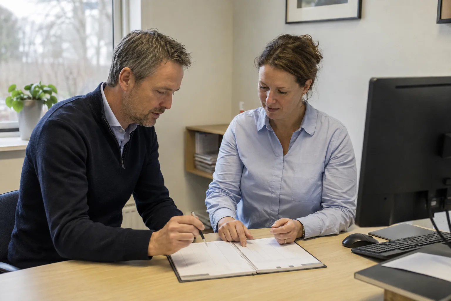 Een man en vrouw bespreken samen de planning in een praktijkruimte.
